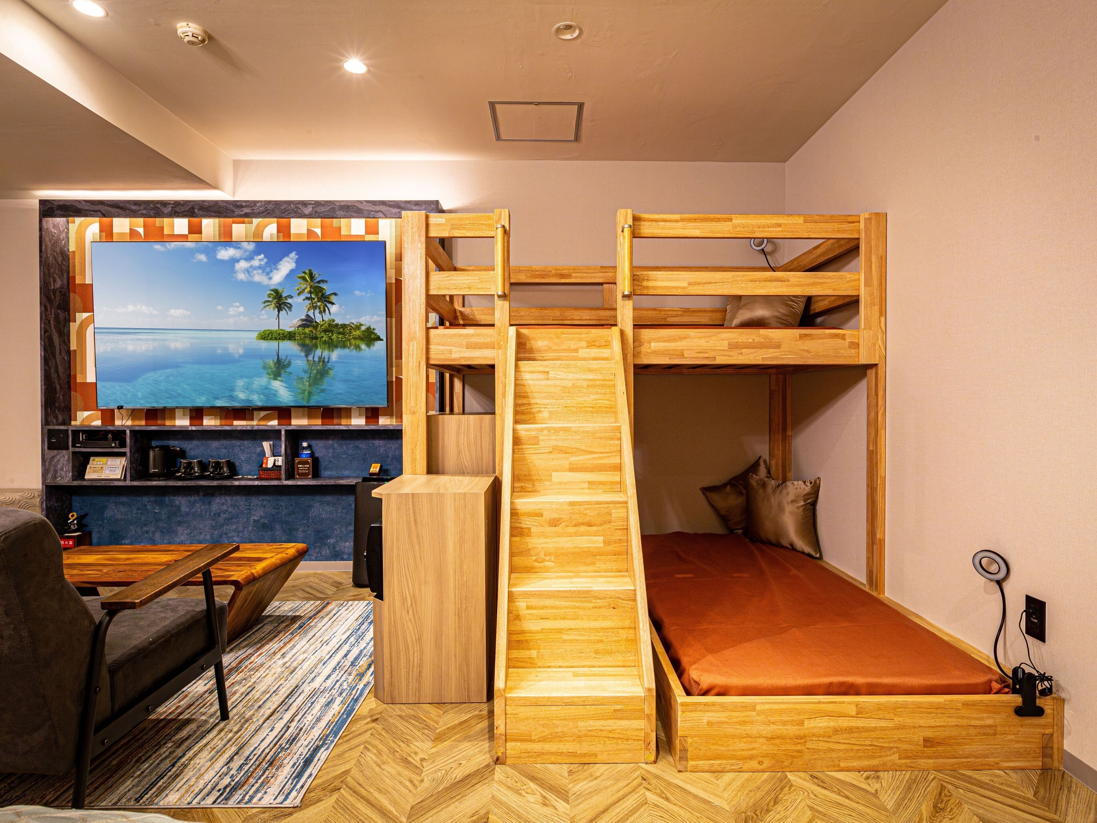 A room with a bunk bed, a desk, a chair, a TV, and a coffee machine.