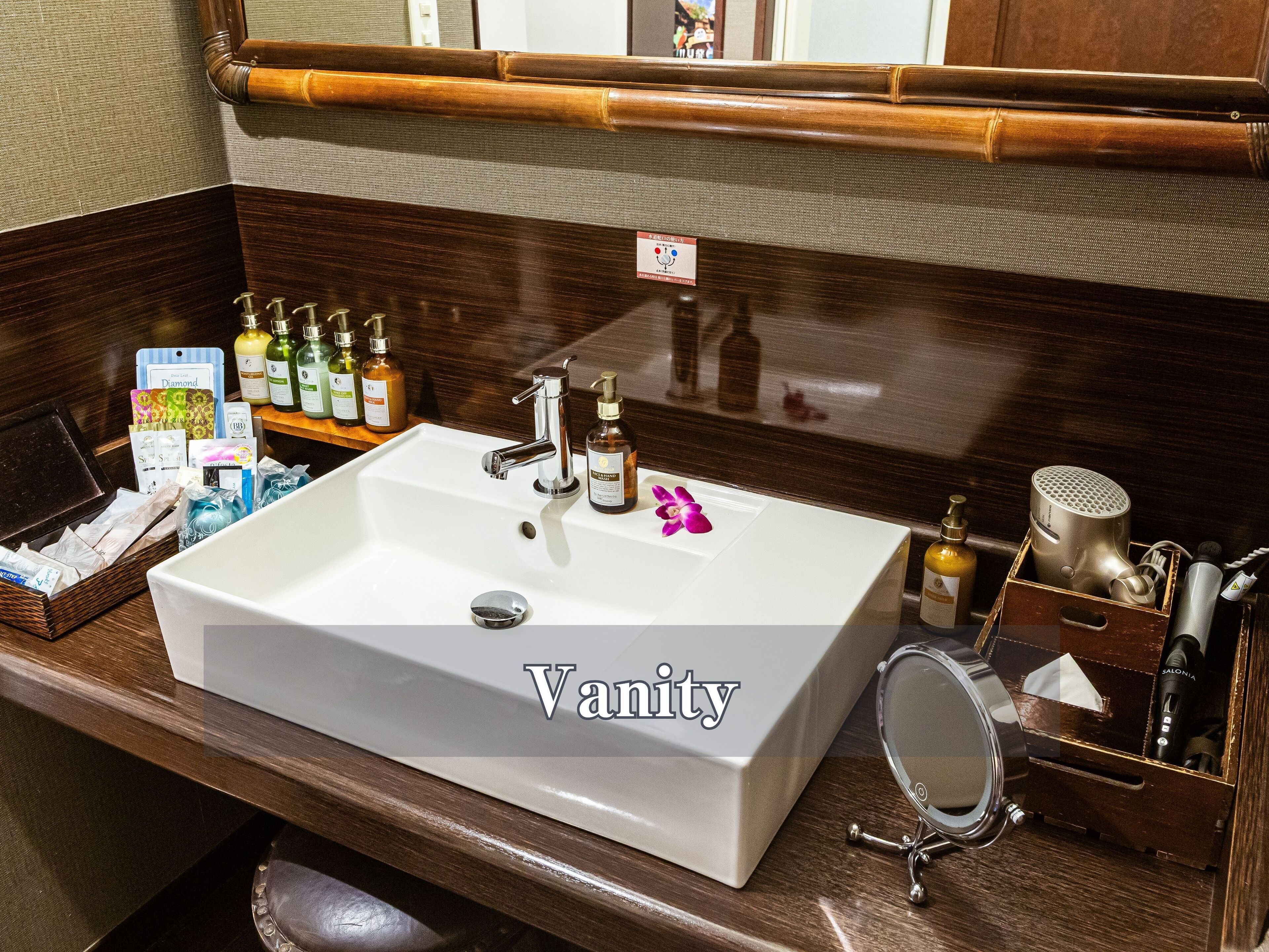 A bathroom with a large white sink, a mirror, and various toiletries on the counter.