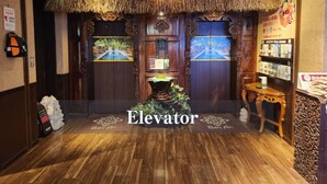An elevator with a thatched roof and wooden doors, leading to a room with a wooden floor and a 'Bali' doormat. - Hotel Balian Resort Shinjuku Honten (Tokyo)