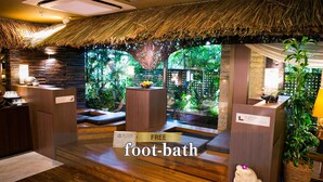 A foot-bath area with wooden flooring, a thatched roof, and a view of a lush garden. - Hotel Balian Resort Shinjuku Honten (Tokyo)