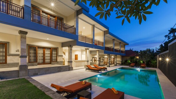 A two-story building with a swimming pool, outdoor seating, and a balcony. - Kubu Petitenget Suite Seminyak (Keroboken Kelod)
