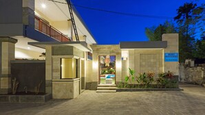 A modern building with a well-lit entrance, a visible sign, and a paved driveway. - Kubu Petitenget Suite Seminyak (Keroboken Kelod)