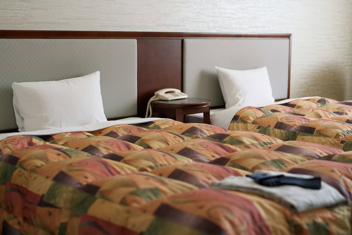 A hotel room with two beds, a bedside table, and a telephone.