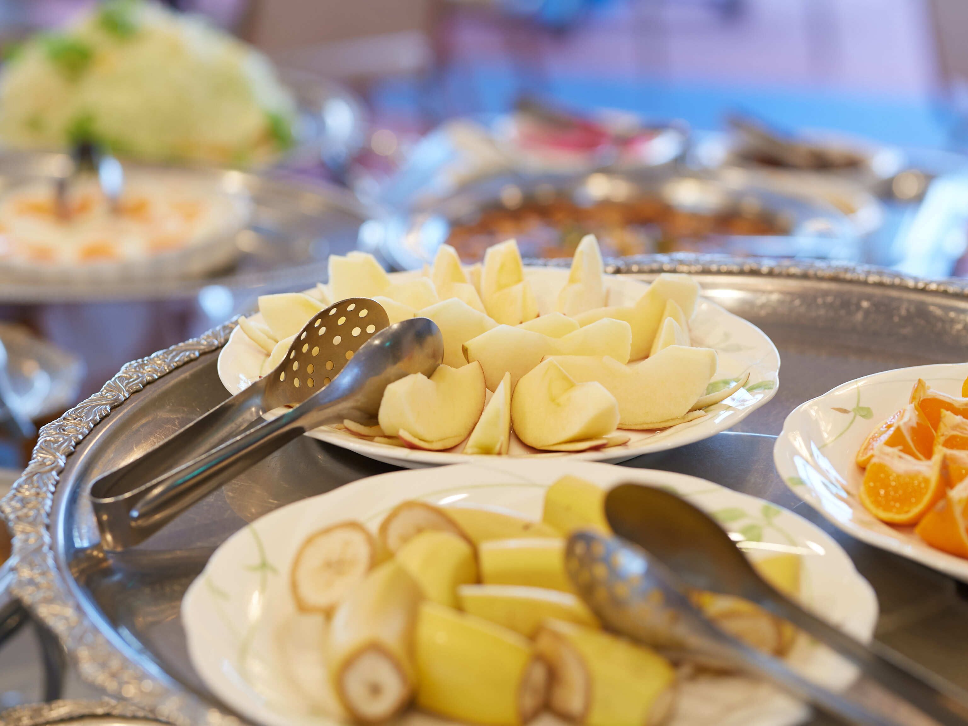 En buffet med forskellige frugter og grøntsager anrettet på fade.