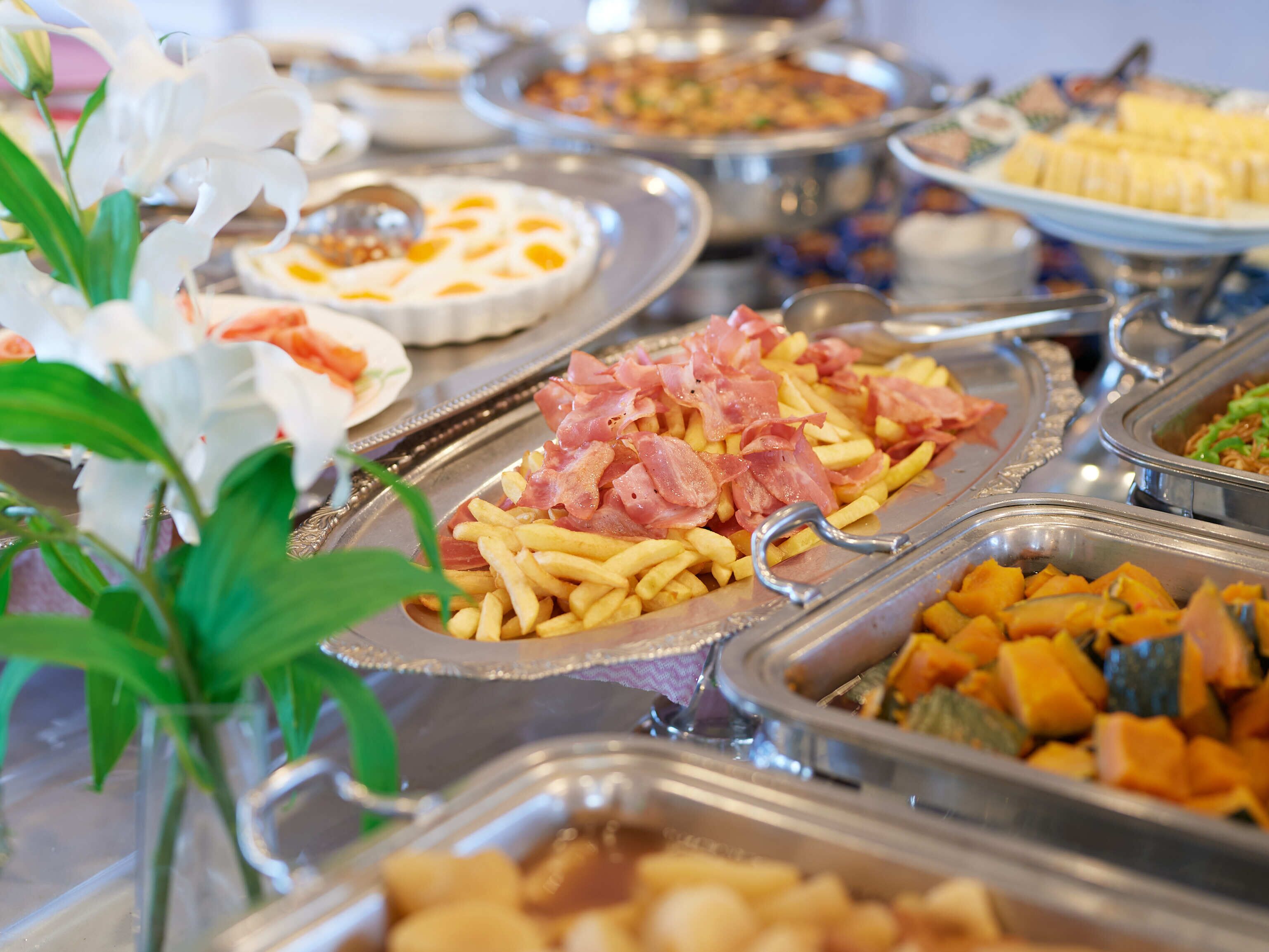 Ein reichhaltiges Buffet mit verschiedenen Speisen, darunter Schinken, Pommes und Gemüse.