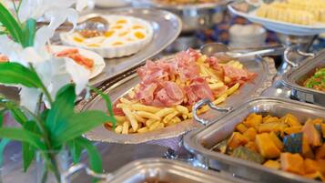 Ein reichhaltiges Buffet mit verschiedenen Speisen, darunter Schinken, Pommes und Gemüse.