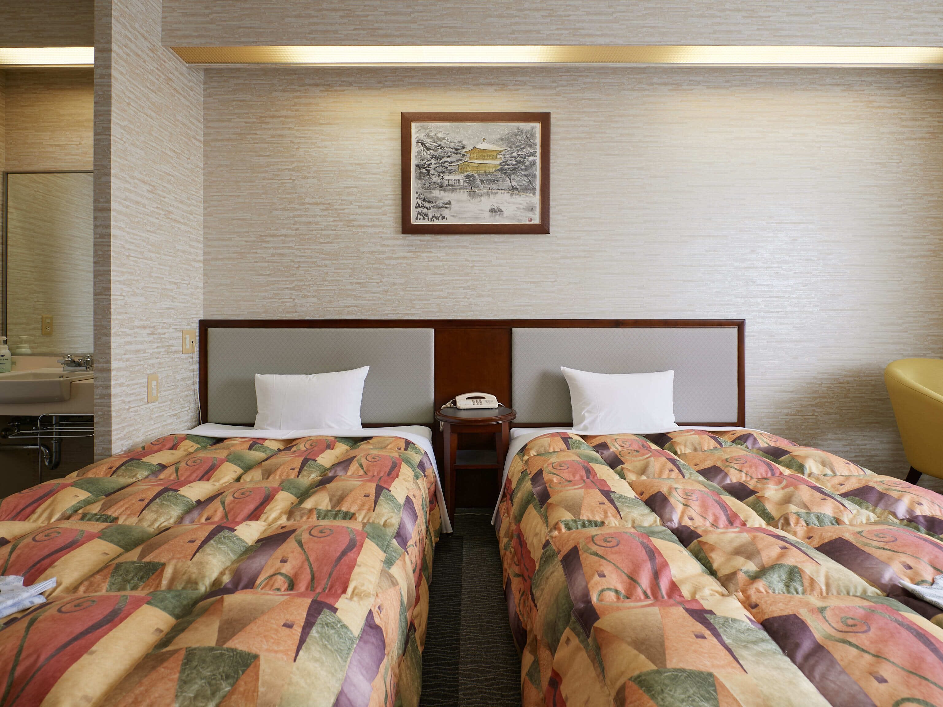 A hotel room with two beds, a nightstand, a telephone, and a painting on the wall.
