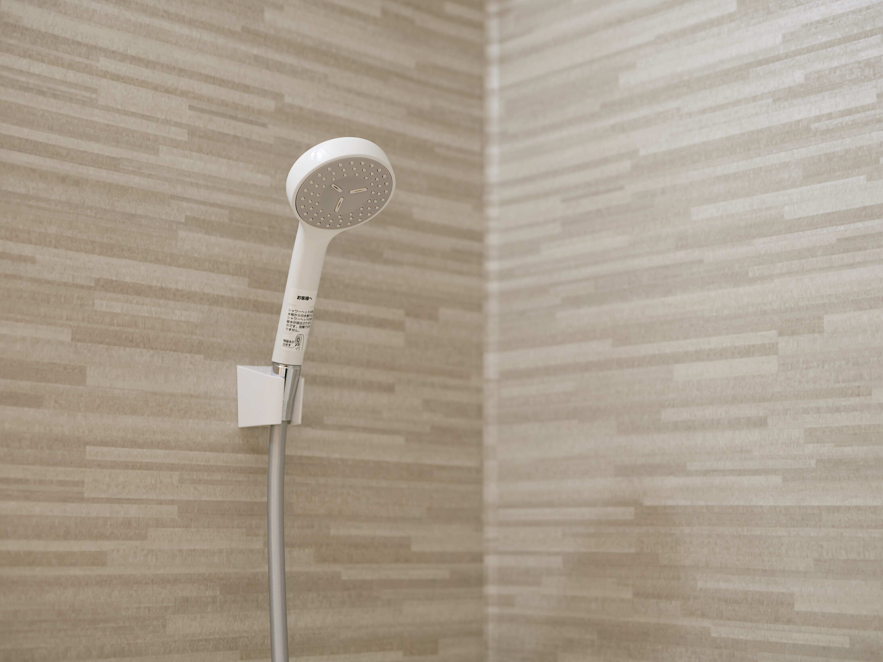 Un cabezal de ducha montado en una pared con diseño de azulejos.
