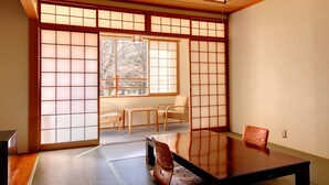 Una habitación japonesa tradicional con suelo de tatami, una mesa baja y puertas correderas.