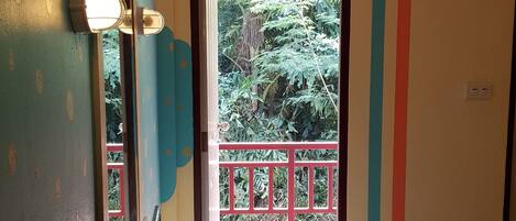 A room with a bathroom vanity, a mirror, and a window with a view of greenery outside.