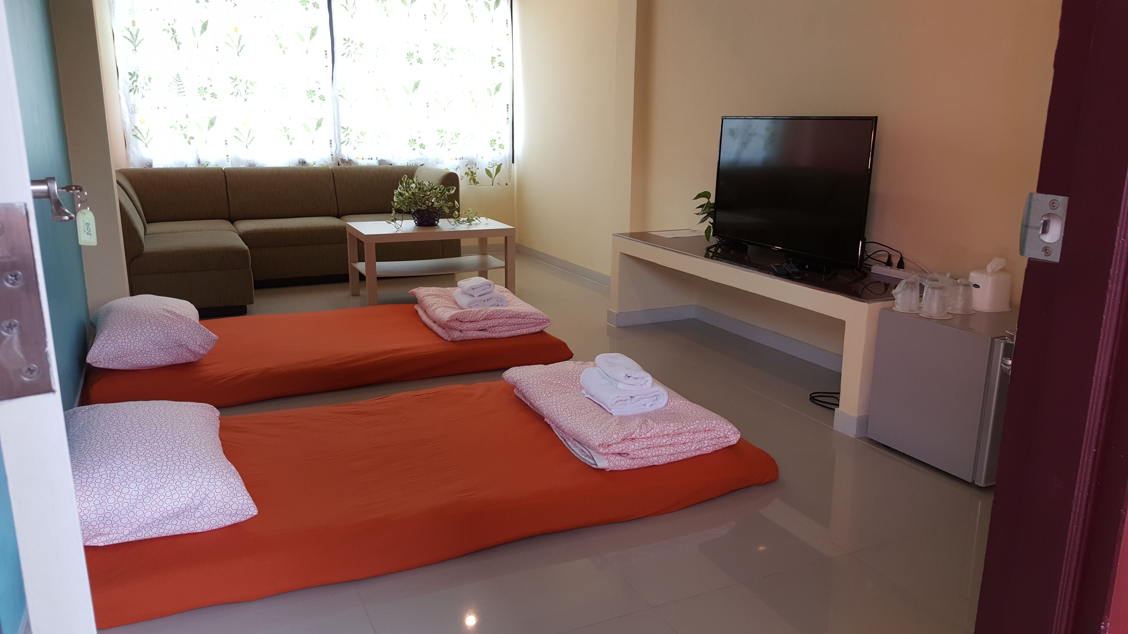 Una habitación con dos camillas de masaje, un sofá, un televisor y una mesita con plantas.