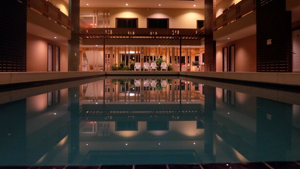 A hotel lobby with a central pool, seating areas, and a reception desk. - Juntima Place at Amphawa (Amphawa)