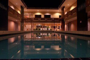 A hotel lobby with a central pool, seating areas, and a reception desk. - Juntima Place at Amphawa (Amphawa)