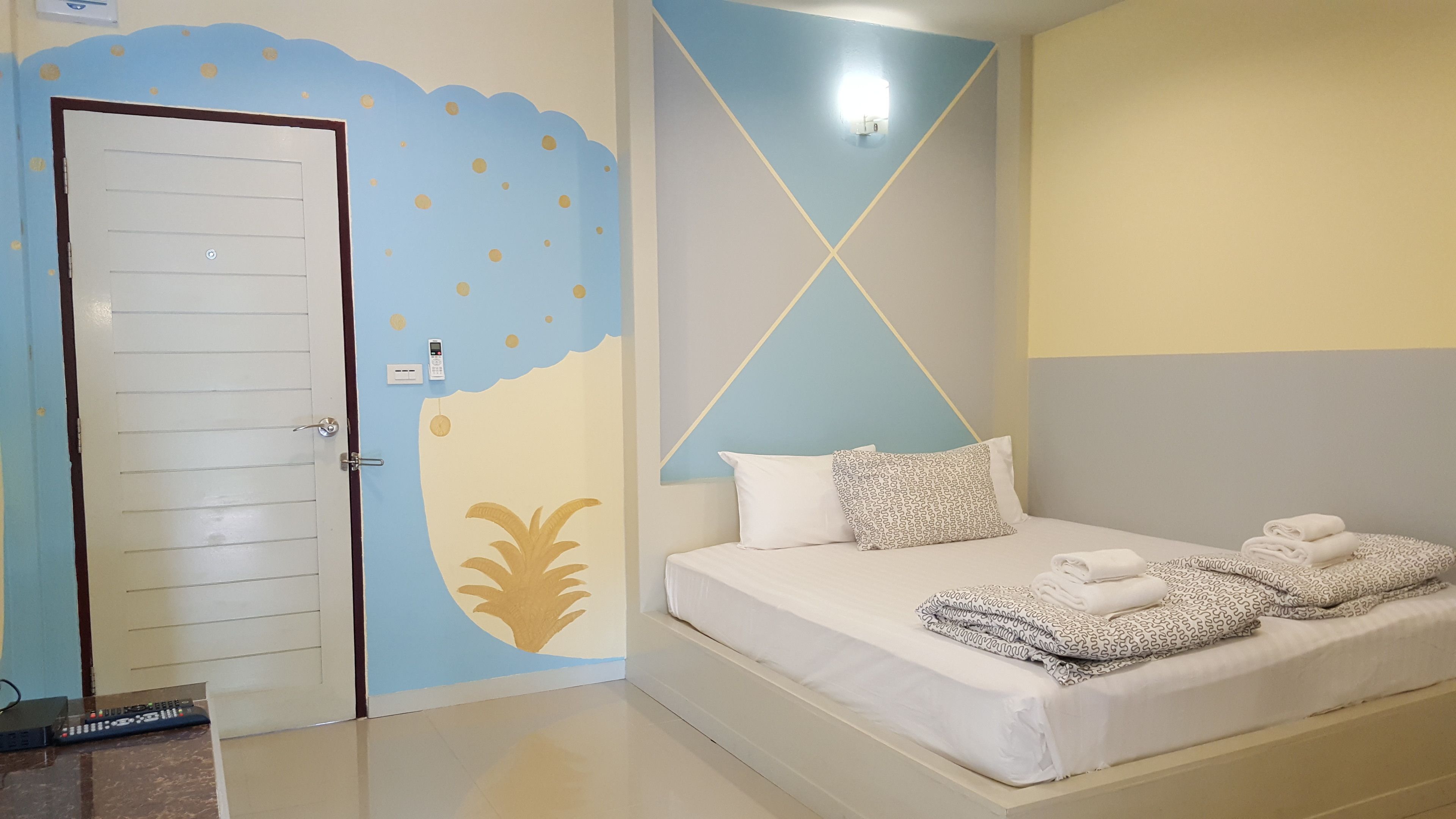 A hotel room with a bed, a door, and a wall with a geometric design.