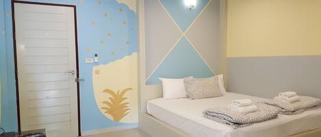 A hotel room with a bed, a door, and a wall with a geometric design.