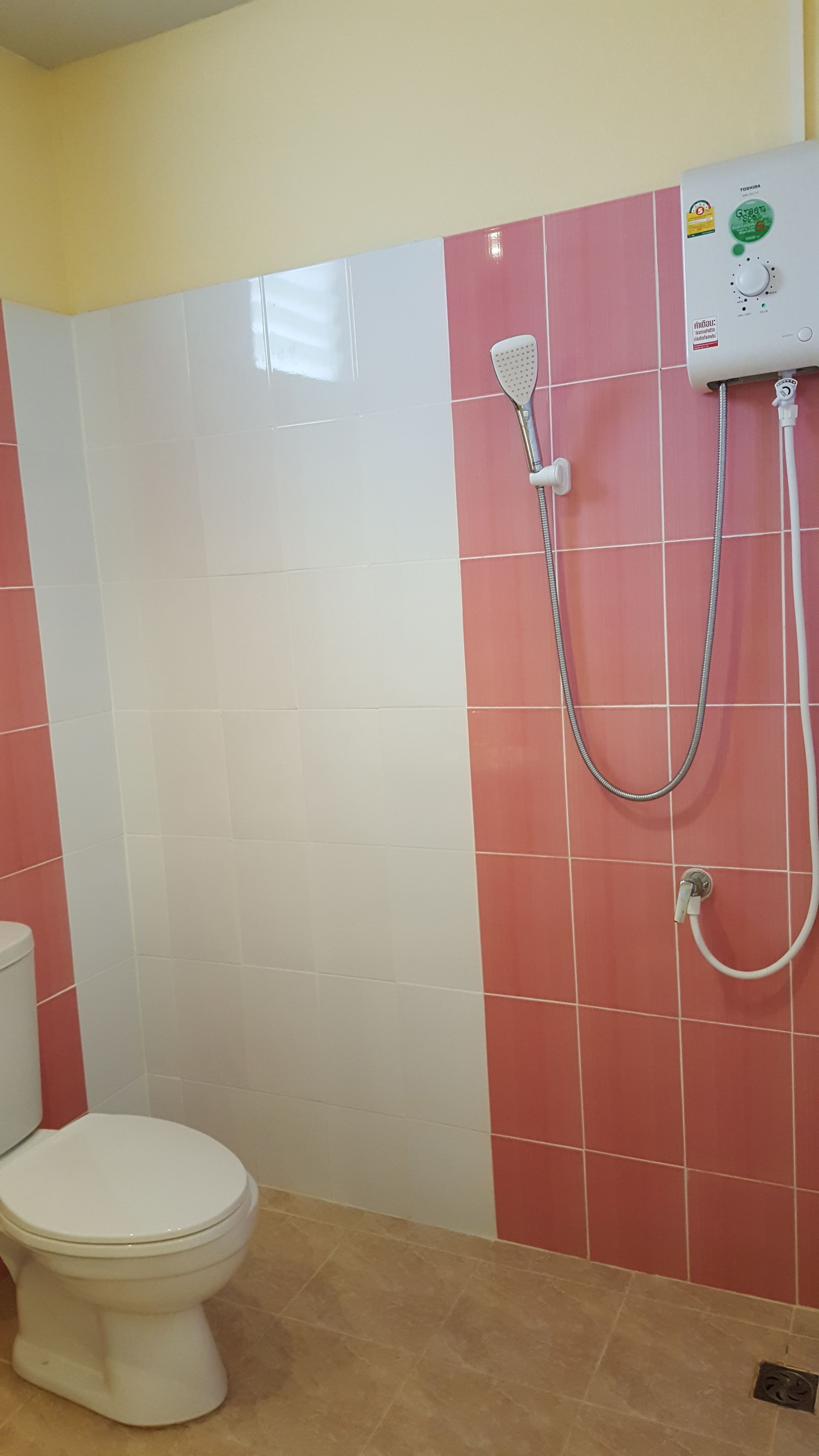 A bathroom with a toilet, a shower unit, and tiled walls.