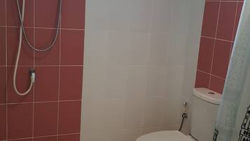 Een badkamer met toilet, douche en raam.