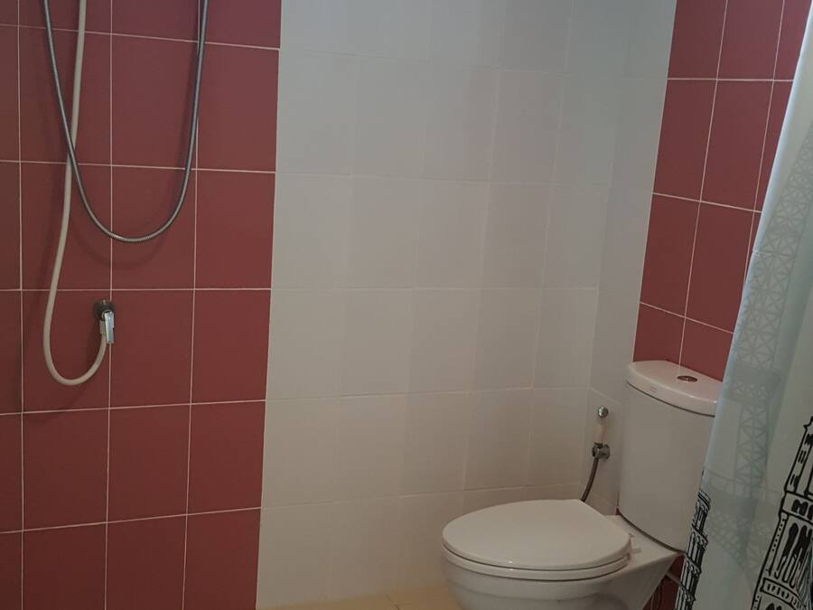 Een badkamer met toilet, douche en raam.
