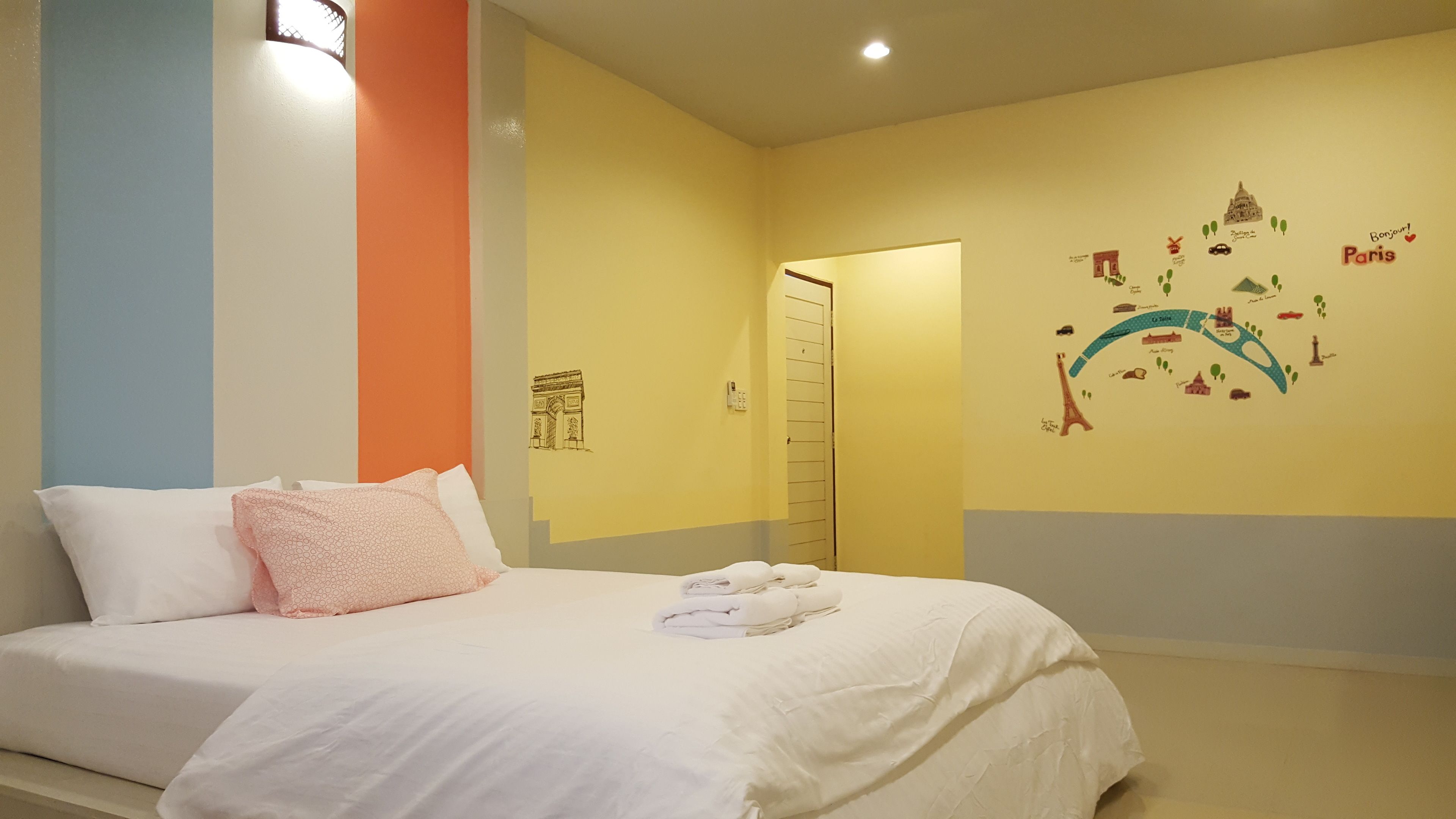A hotel room with a bed, pillows, and a wall map of Paris.