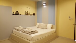 A hotel room with a bed, a cityscape wall art, a door, and a light fixture. - Juntima Place at Amphawa (Amphawa)