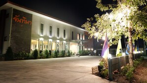 A building with a large sign, a paved entrance, and a tree with lights. - Juntima Place at Amphawa (Amphawa)