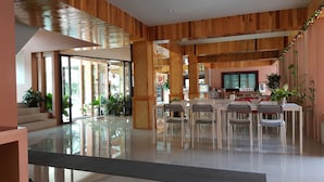 A spacious, modern interior with a central dining area, wooden paneling, and potted plants. - Juntima Place at Amphawa (Amphawa)