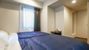 A hotel room with two beds, a small bedside table, an air conditioning unit, and a window with curtains. - Hotel Livemax Tokyo Bakurocho (Tokyo)