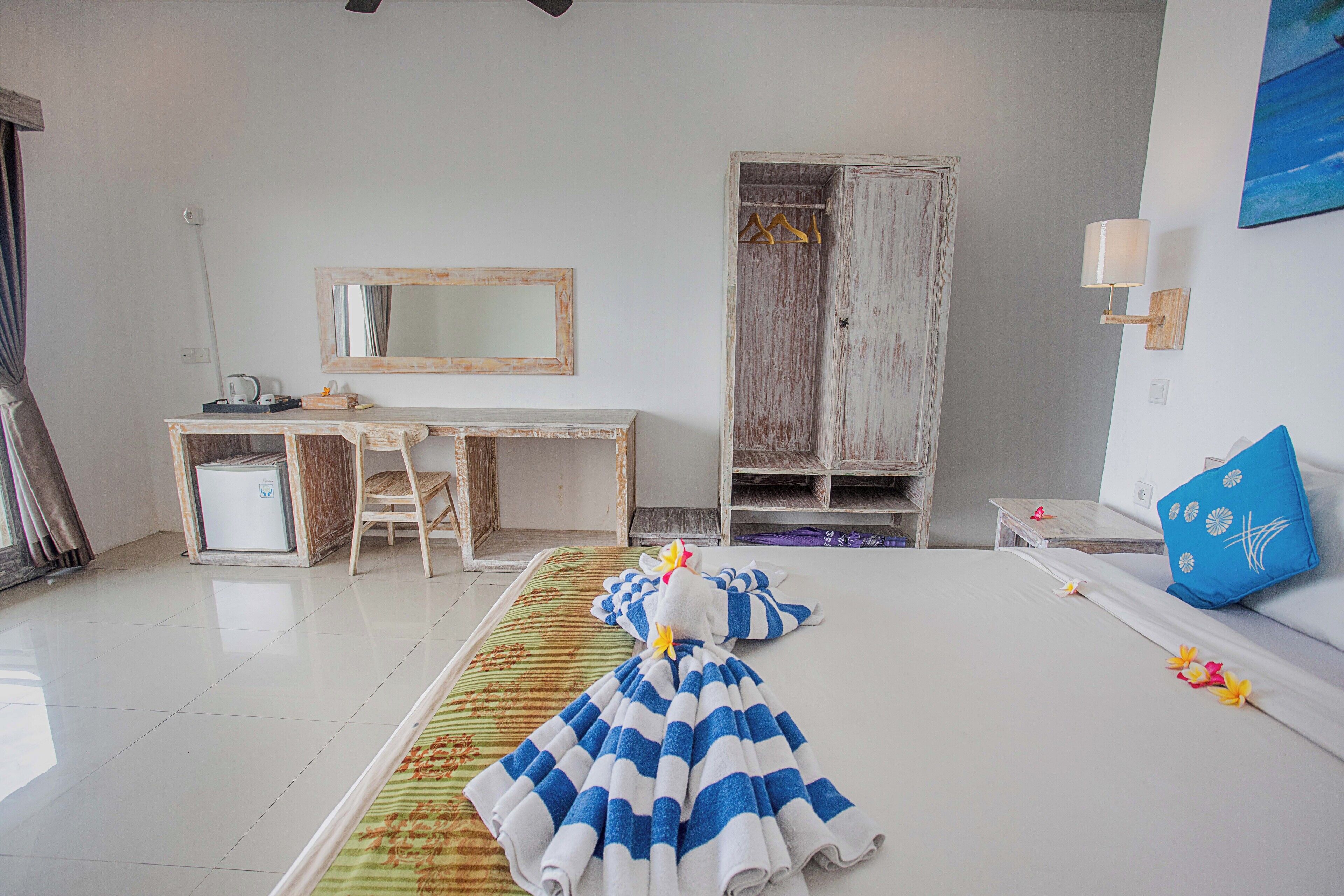A hotel room with a bed, a desk, a wardrobe, and a mirror.