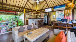 Ein großzügiger Loungebereich mit Korbomöbeln, einer Bar und Blick ins Freie.