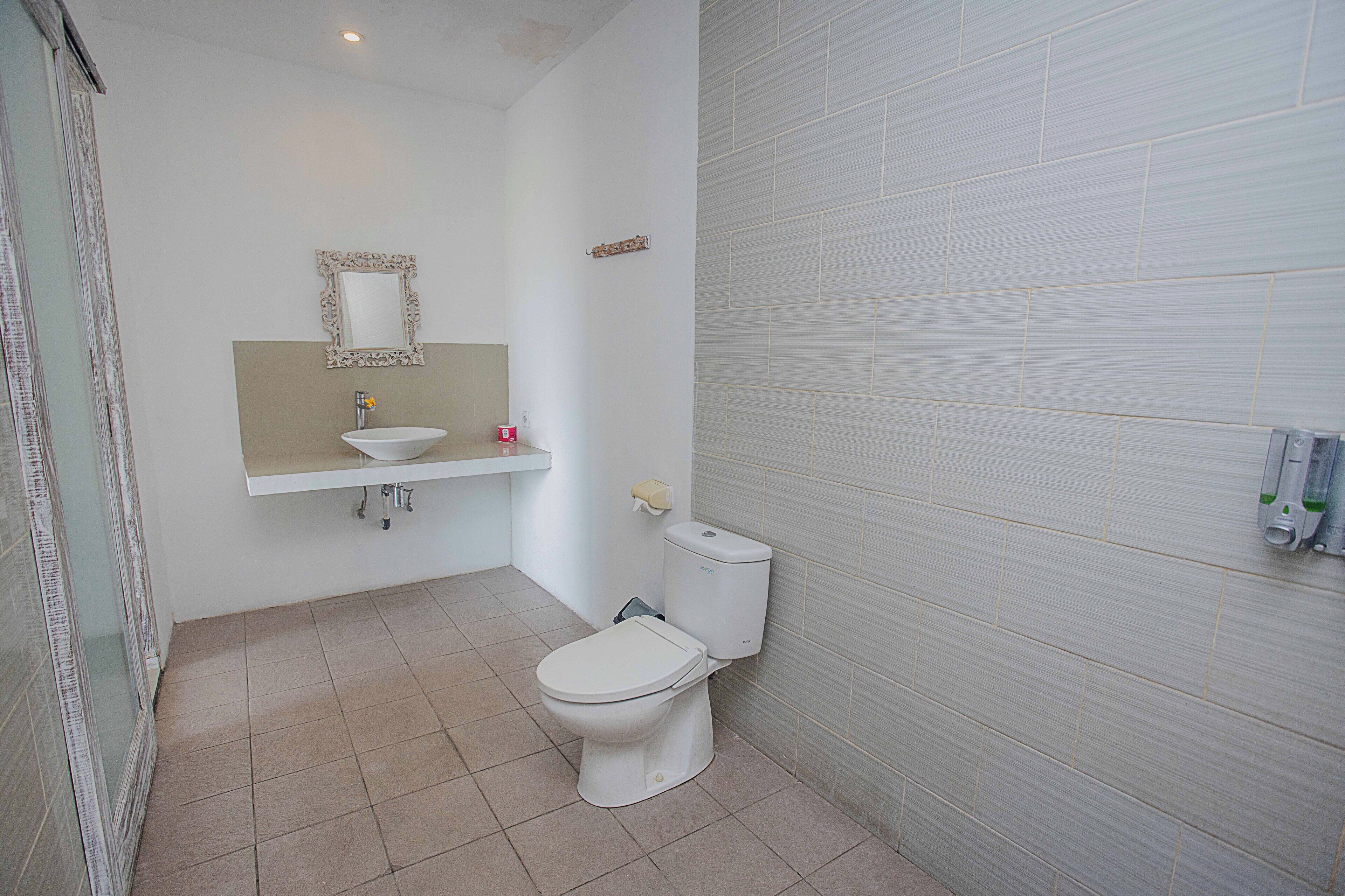A bathroom with a toilet, sink, and mirror.