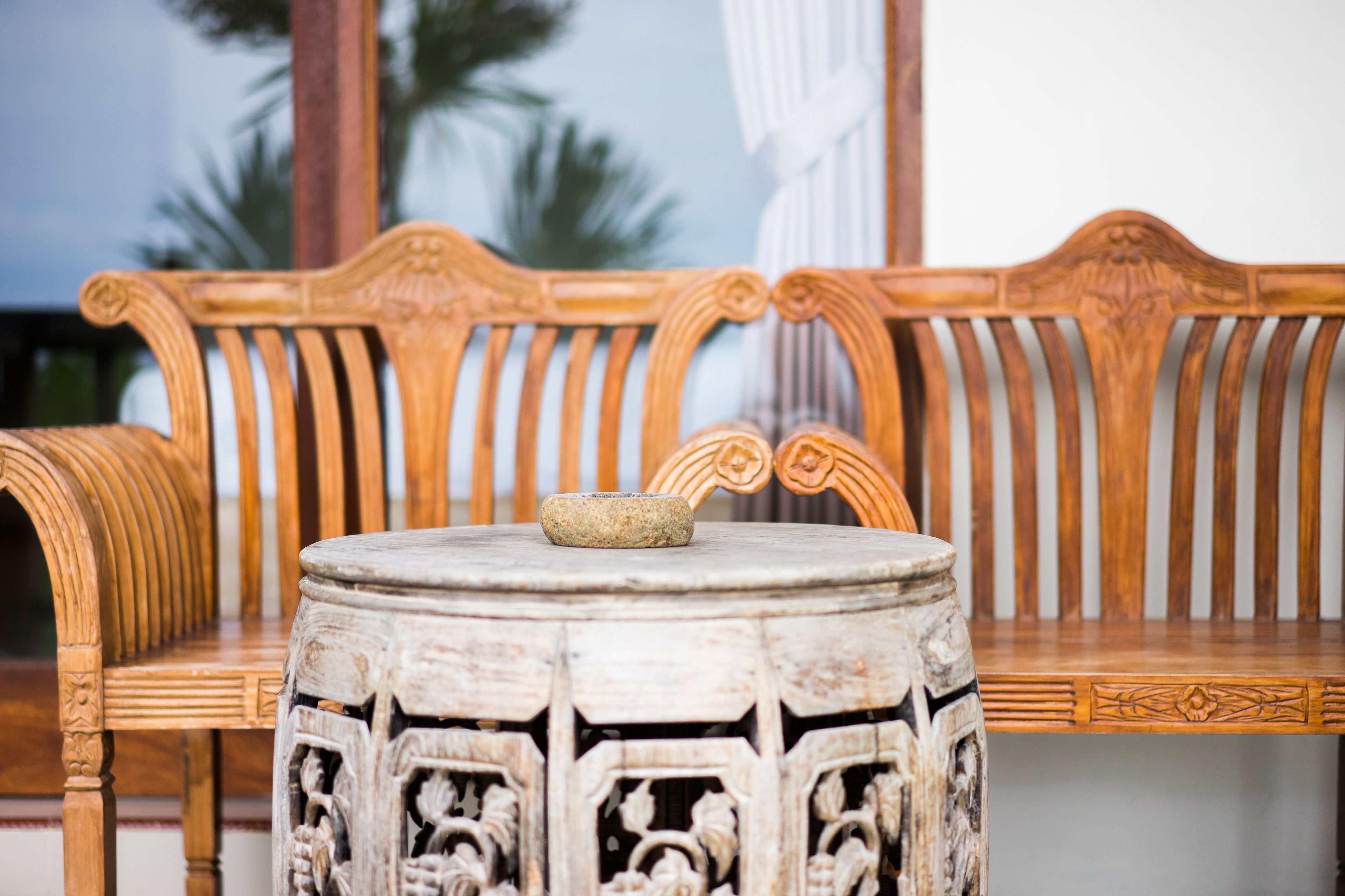A wooden bench with intricate carvings and a stone table in front.
