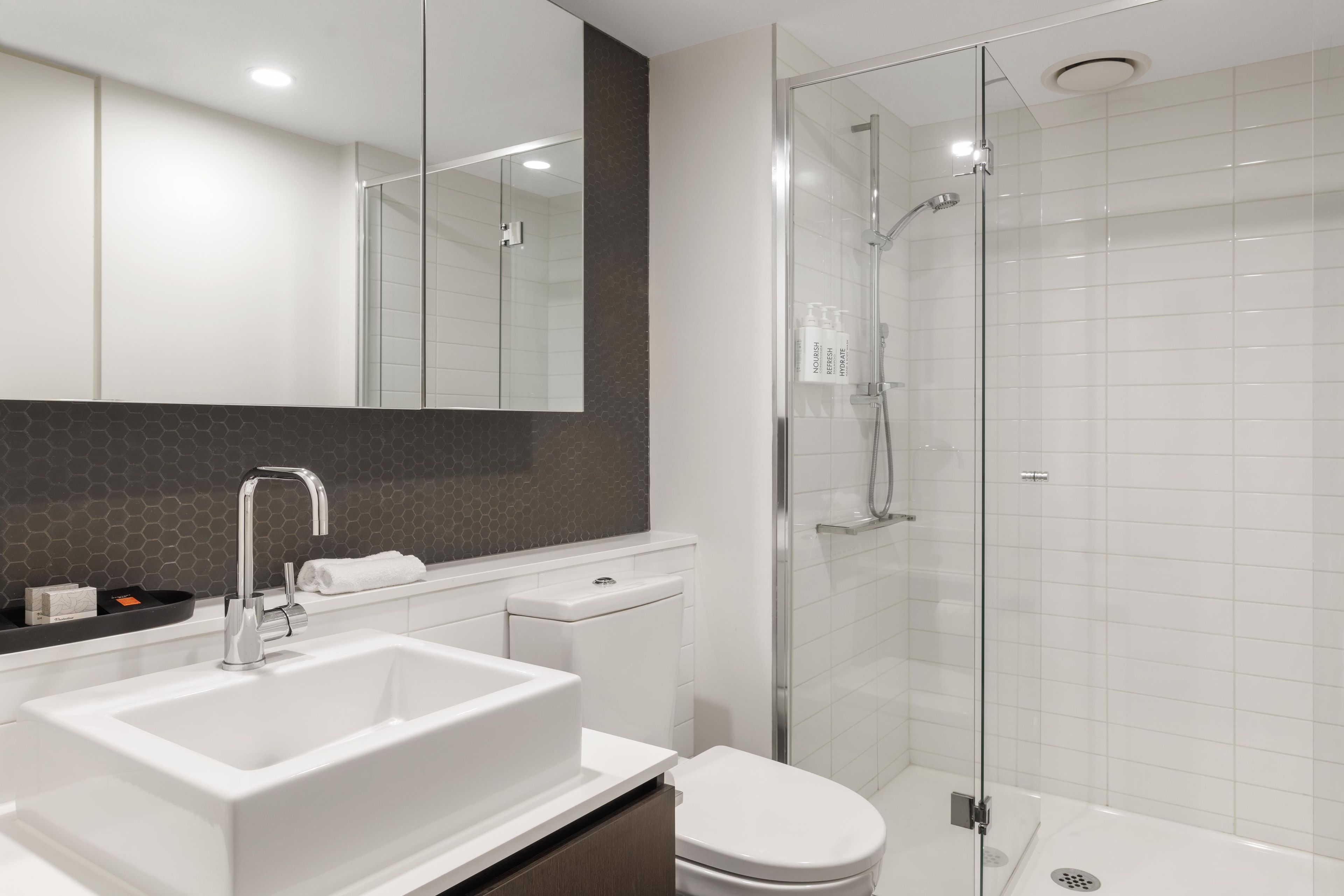 A modern bathroom with a white sink, a toilet, and a glass-enclosed shower.