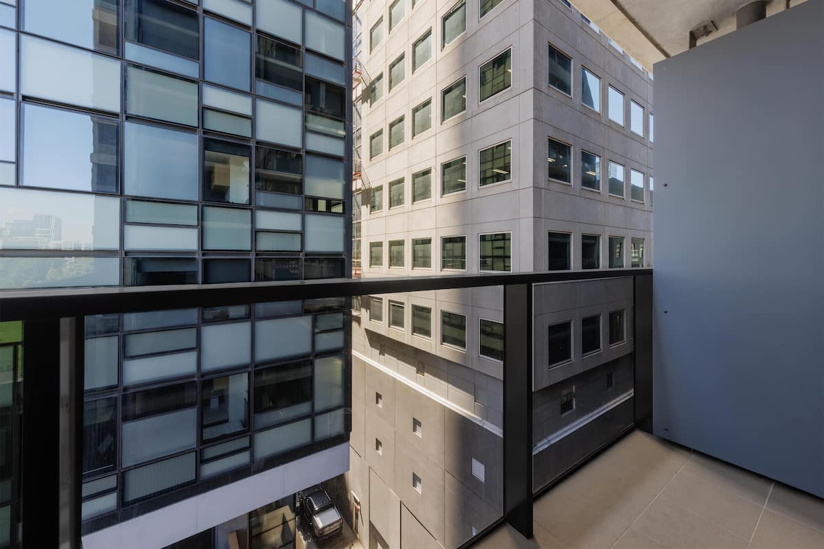 A modern building with multiple floors, large windows, and a balcony area.