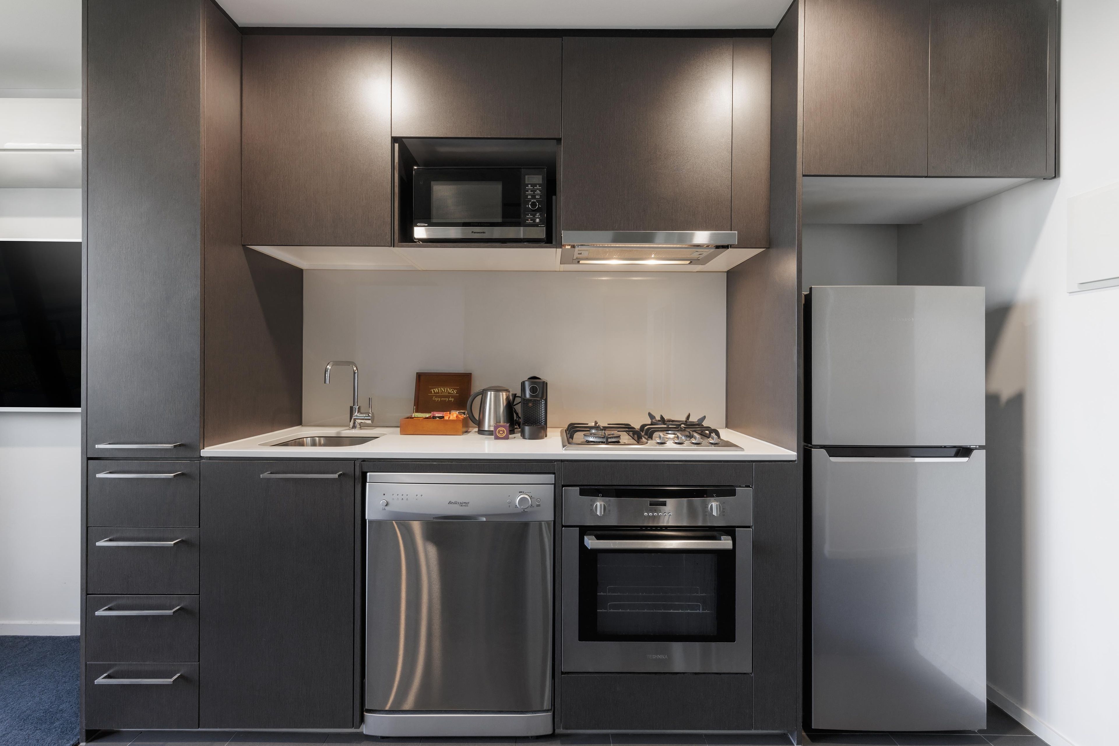 Een moderne keuken met een ingebouwde magnetron, oven en koelkast.