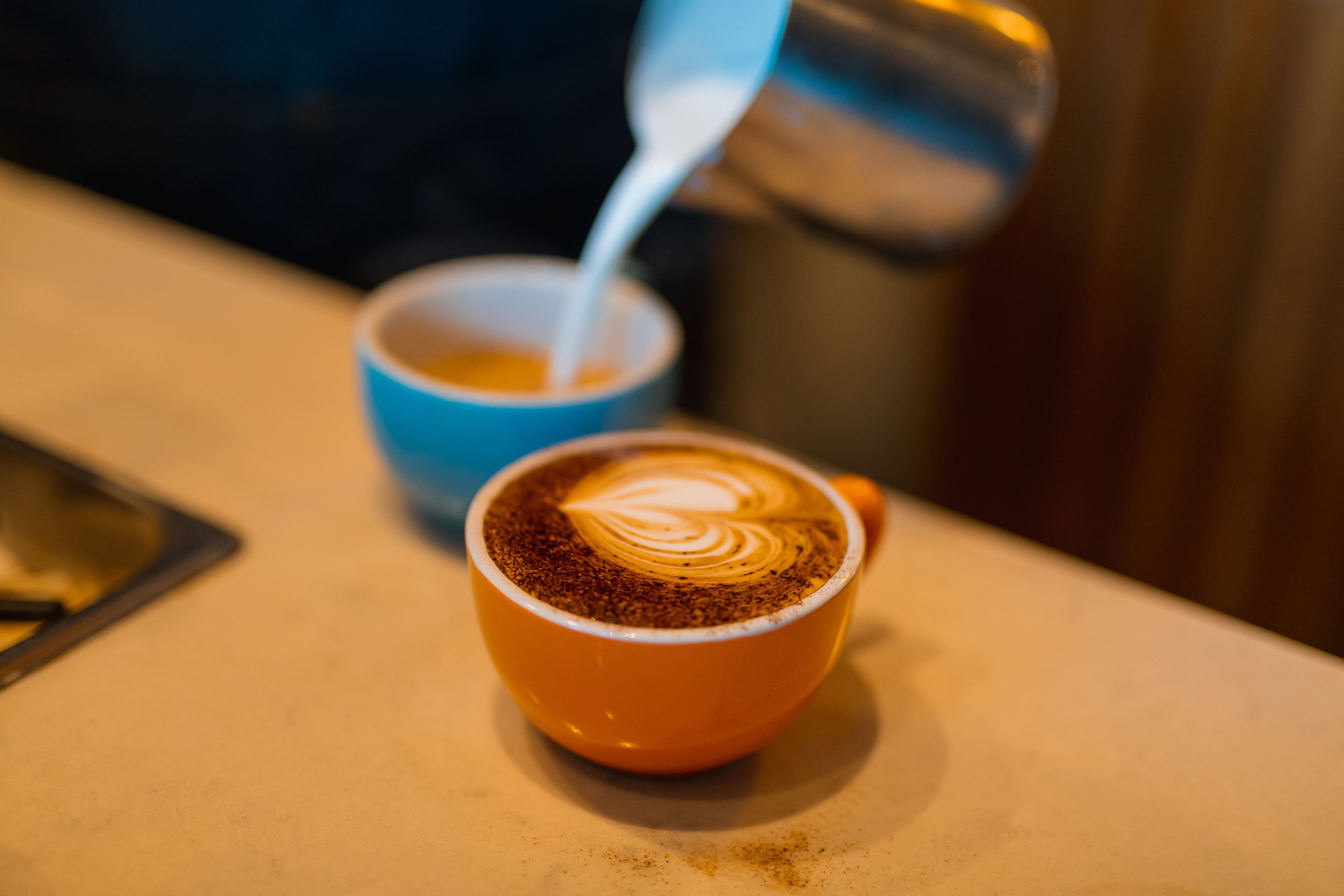 Un gros plan d’une tasse de café sur une table, avec un motif artistique réalisé avec de la mousse de lait.