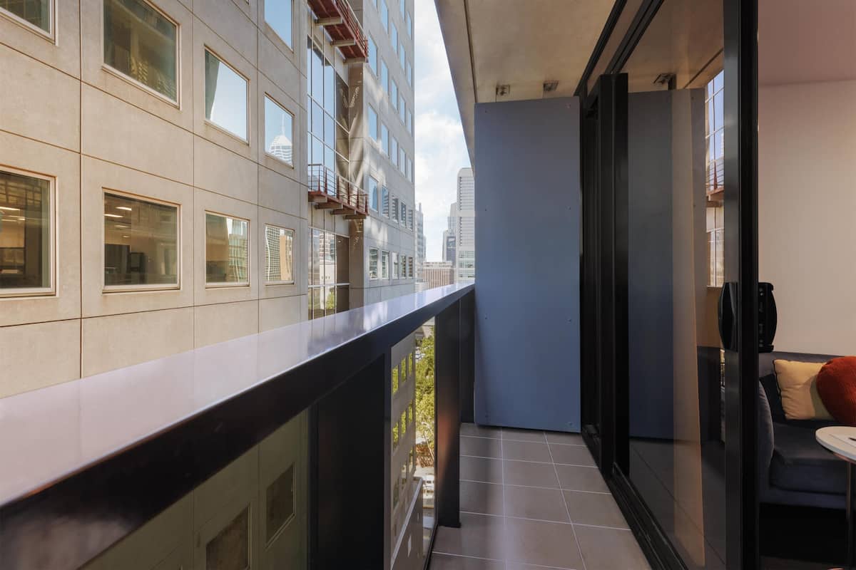 A modern apartment with a balcony, large windows, and a view of the cityscape.