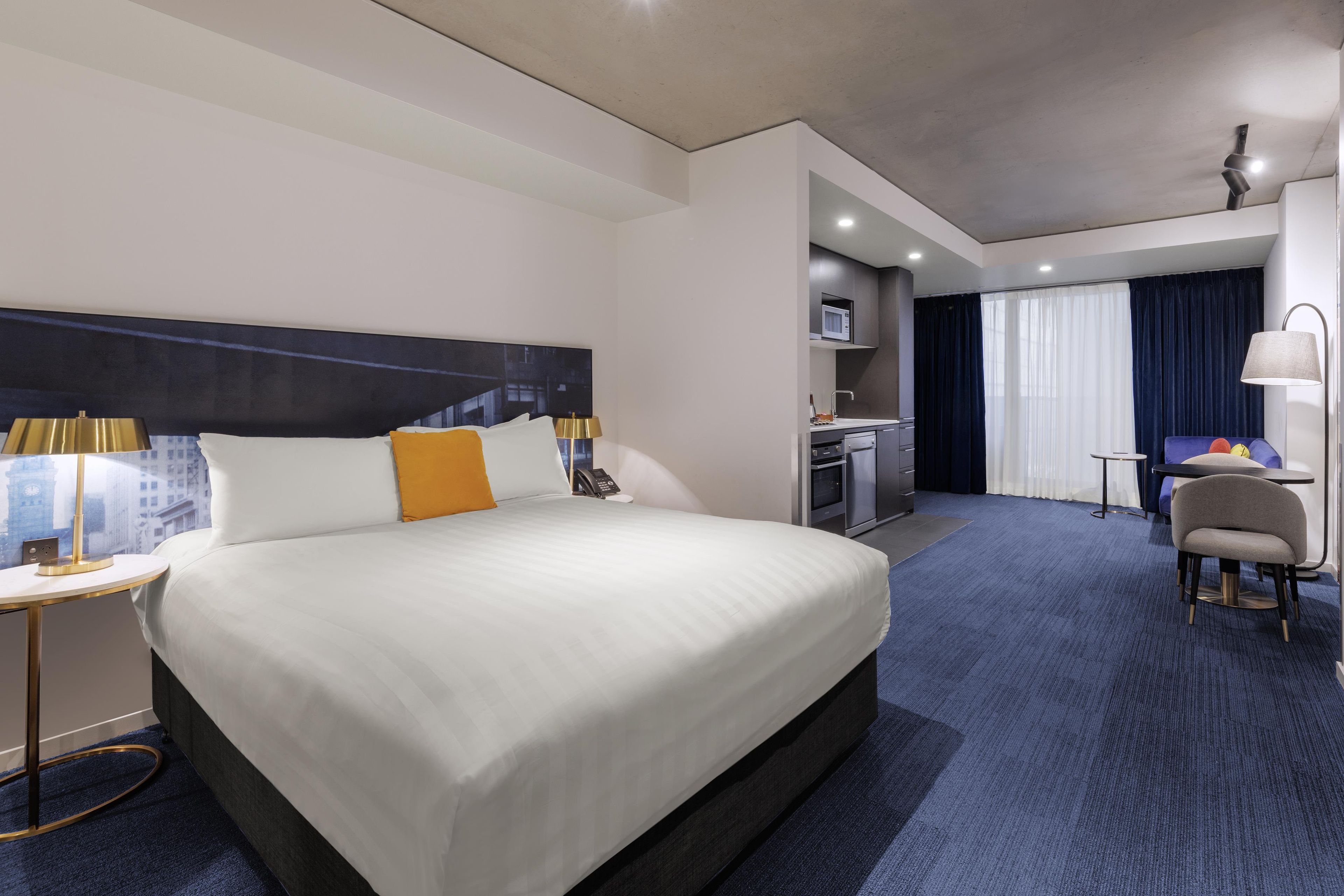 A hotel room with a large bed, bedside tables, a desk, and a chair.