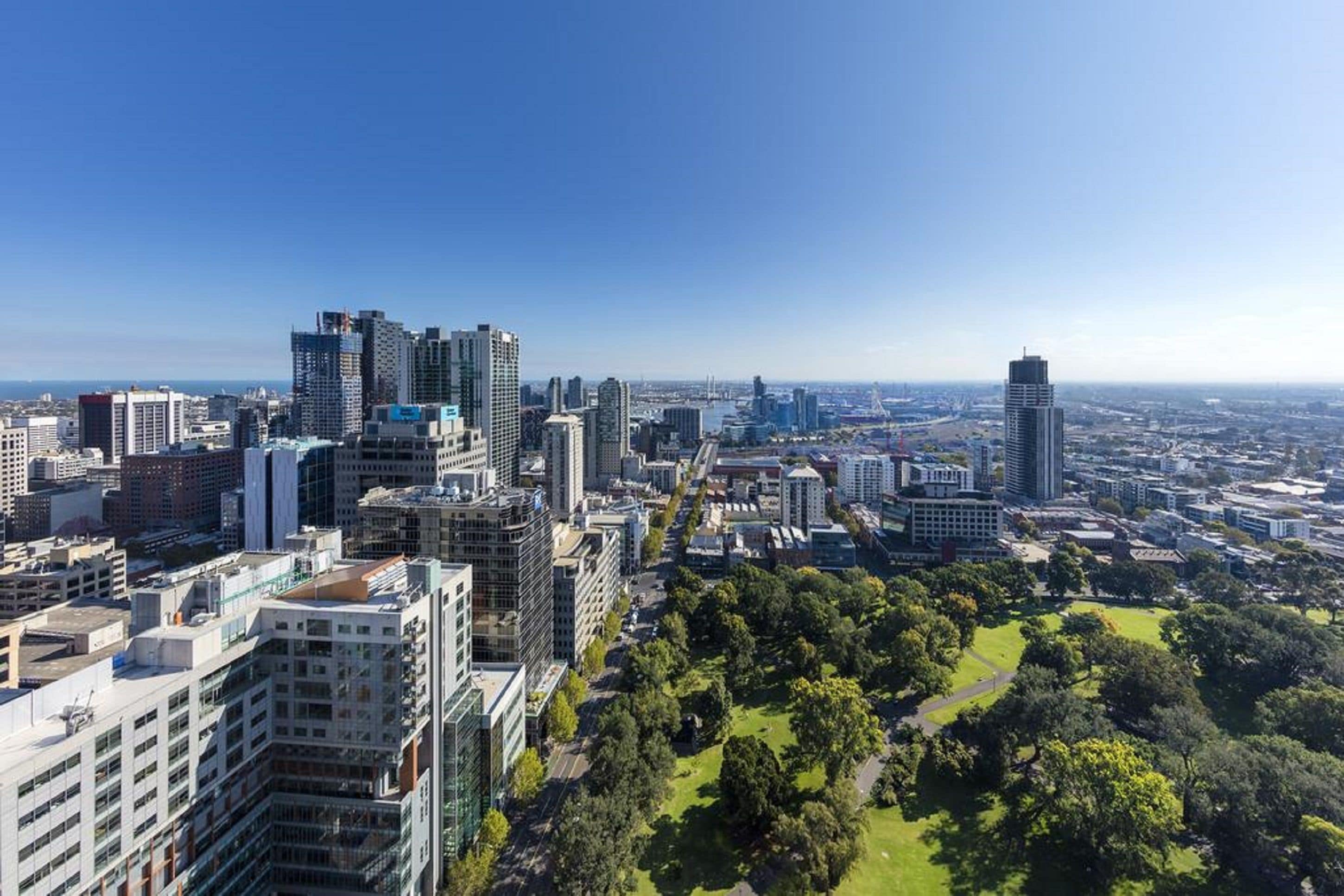 Un paysage urbain avec de hauts immeubles, un grand parc au centre et un ciel dégagé.