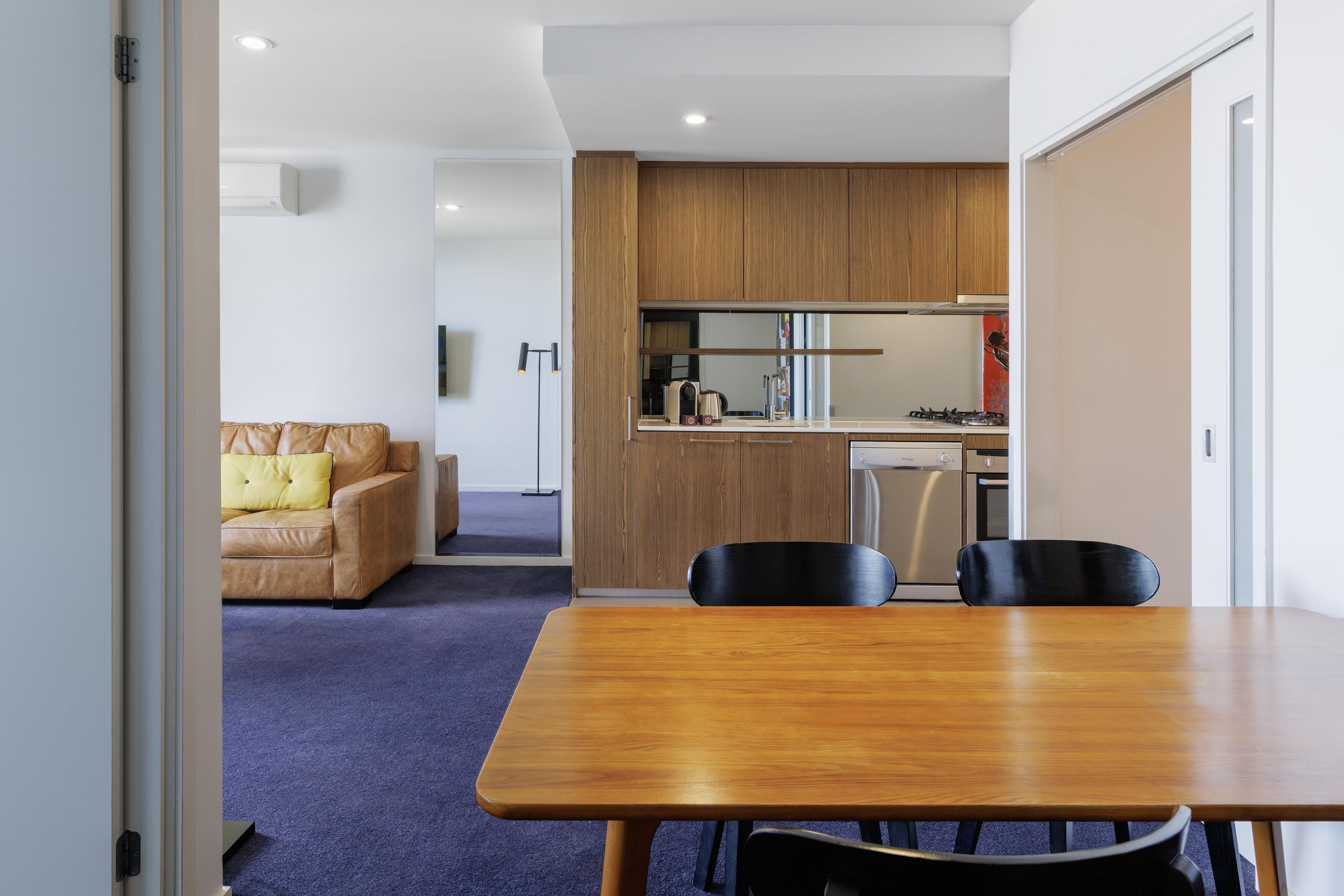 Un intérieur moderne comprenant une table à manger, des chaises, un canapé et un coin cuisine.