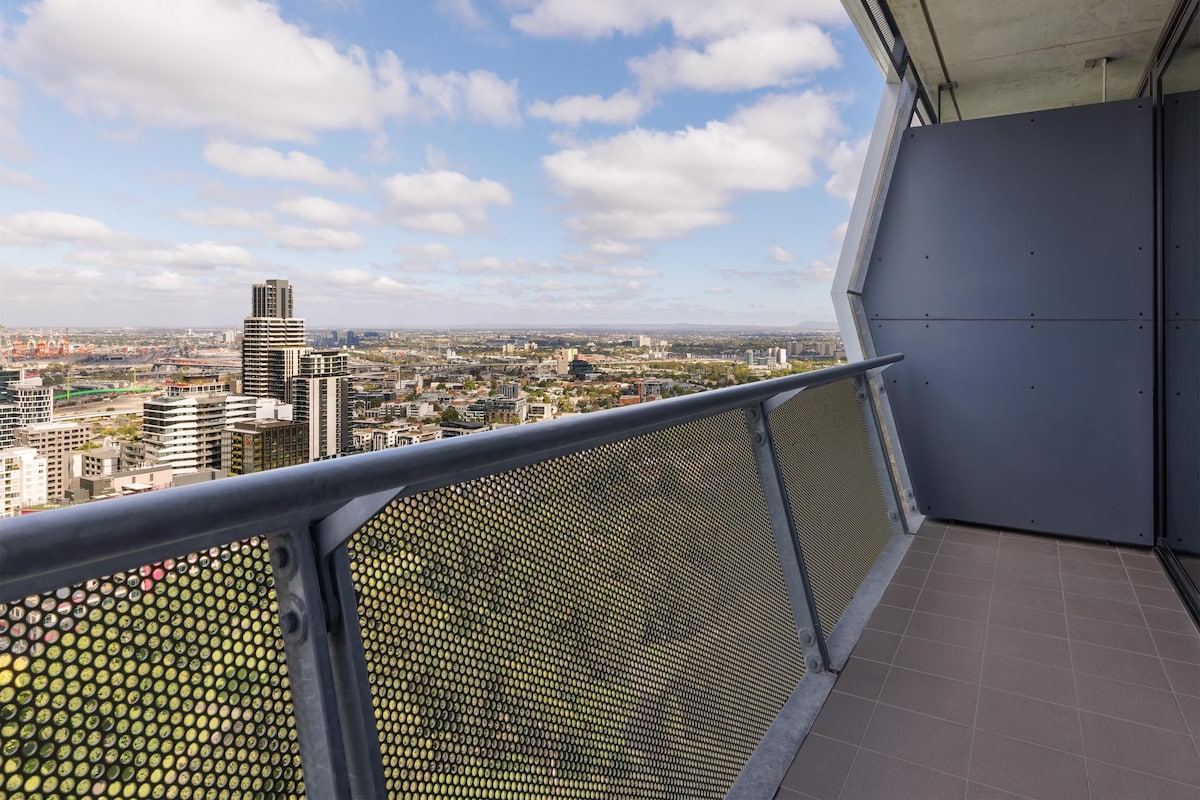 A balcony with a metal railing overlooking a cityscape.