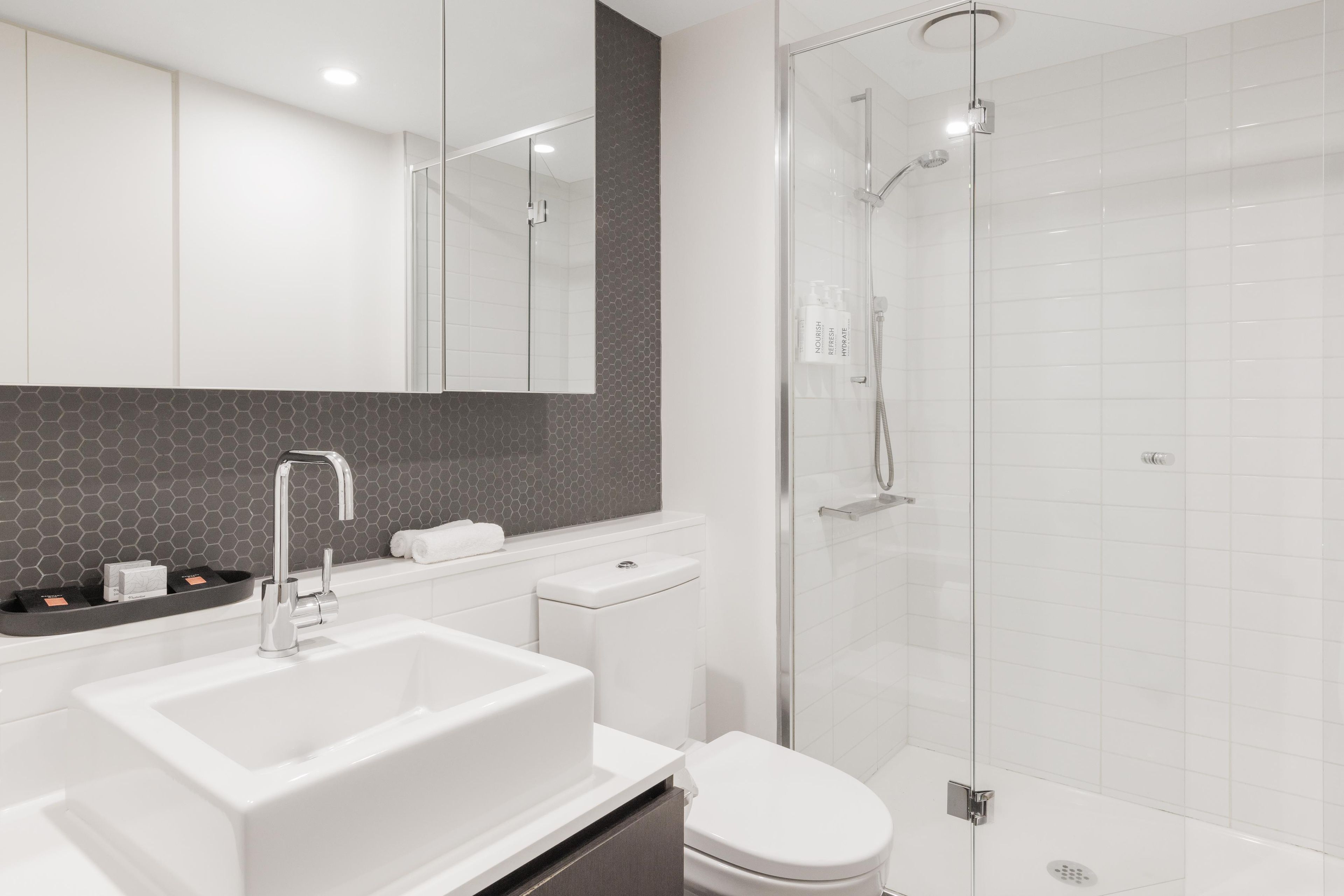 A modern bathroom with a glass-enclosed shower, a white sink, and a toilet.