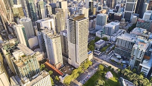 Uma área urbana com edifícios altos e modernos, uma praça central e uma combinação de estruturas comerciais e residenciais.