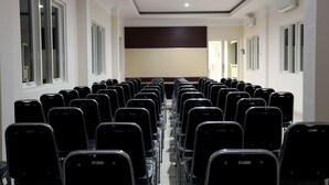 Konferenssisali, jossa on riveittäin tuoleja, ja tuolit on suunnattu kohti lavaa.