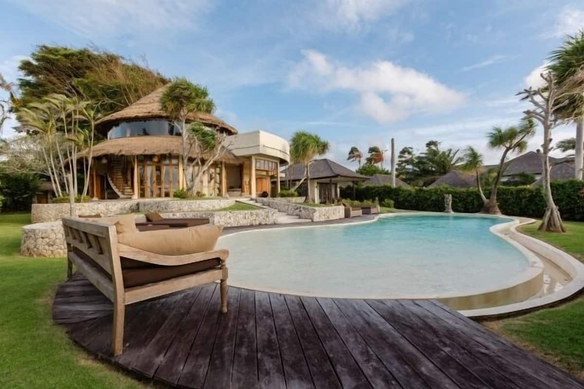 Ein Resort mit Schwimmbad, einer Holzterrasse und strohgedeckten Gebäuden.