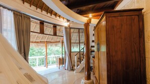 Una habitación amplia con un gran ventanal, un armario de madera y una escalera que conduce a un espacio al aire libre.