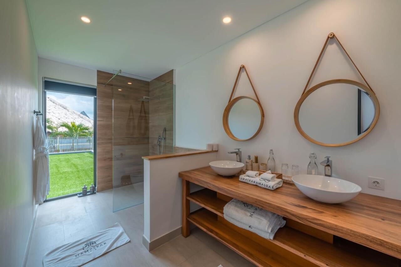 A modern bathroom with two sinks, wooden vanity, and large mirrors.