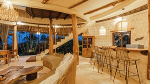 Un salón espacioso con sofá, muebles de madera y una escalera que sube a un nivel superior.