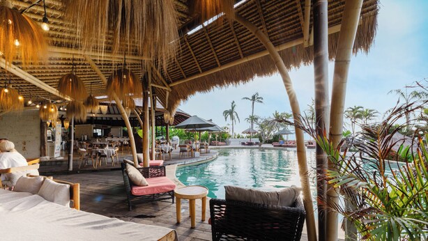 Zona de piscina con sillones reclinables, un bar y vistas a la piscina.