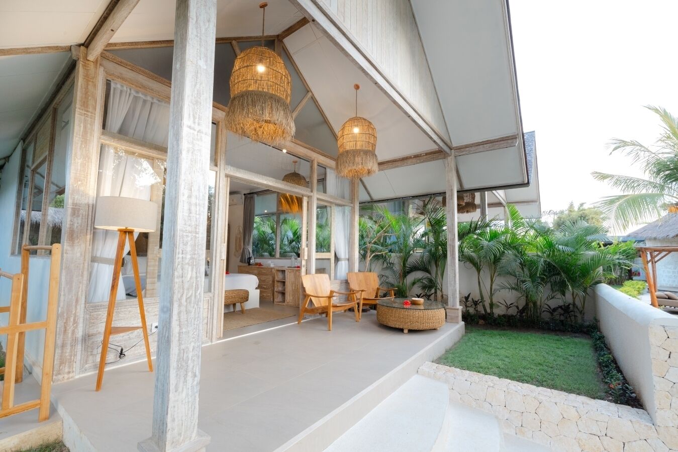 A spacious outdoor area with a seating arrangement, a dining table, and a large window overlooking a garden.