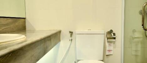 A modern bathroom with a toilet, a sink, and a glass shower enclosure.